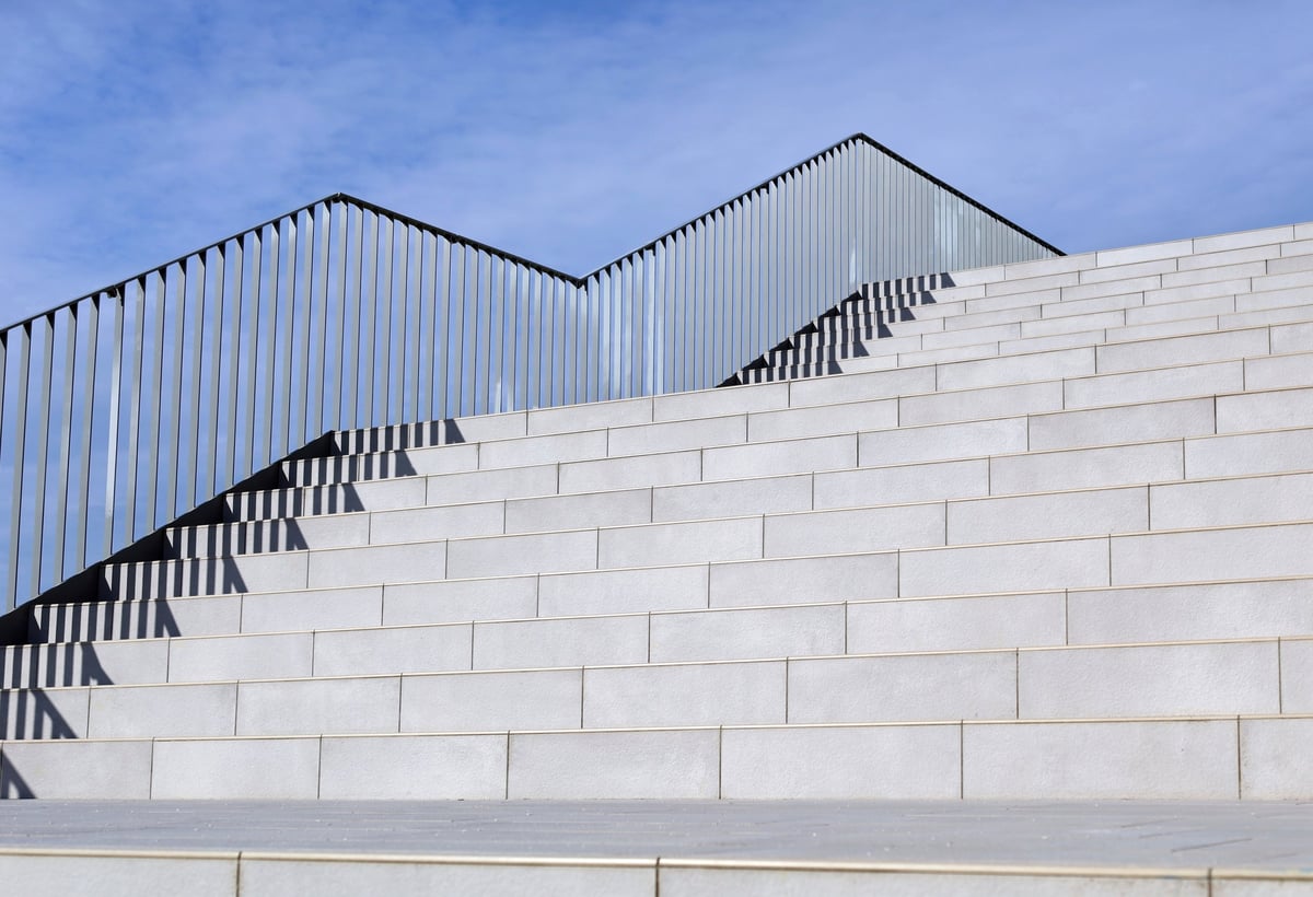 Stone tile stairs with metal railing and blue cloudy sky