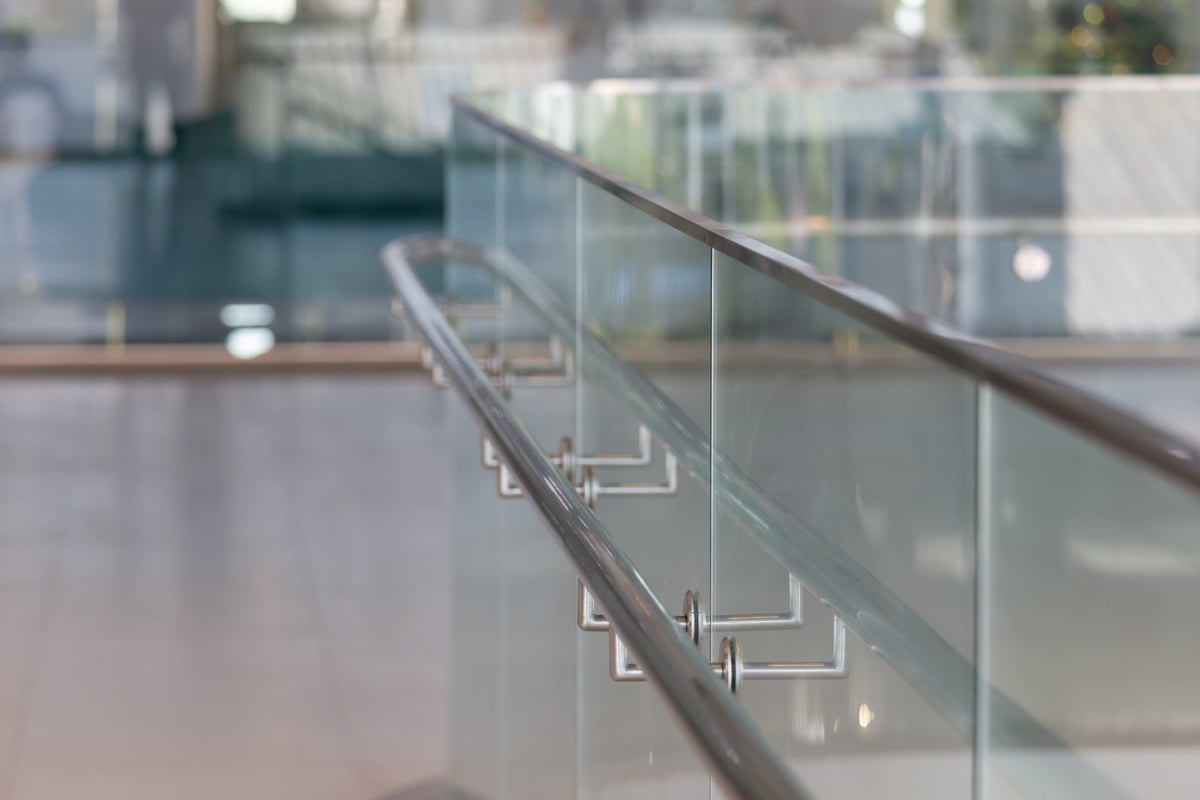 Modern tempered glass and metal railing curves gently through a bright, open space