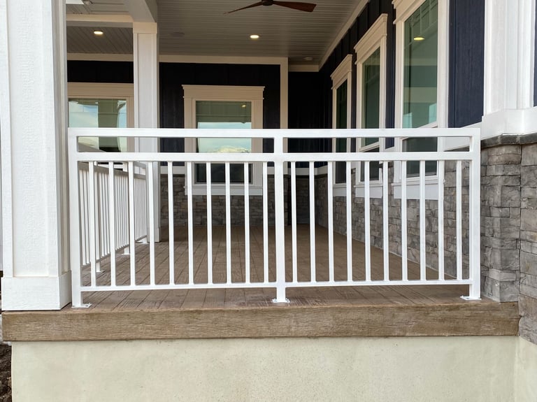 White railing on a front porch or deck with glass doors and black interior visible behind it