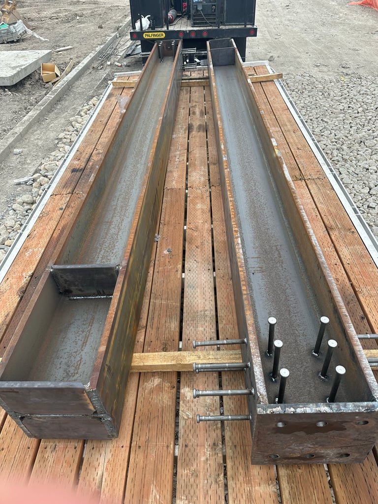 Metal structural beams and channels laid out on a wooden truck bed at a construction site