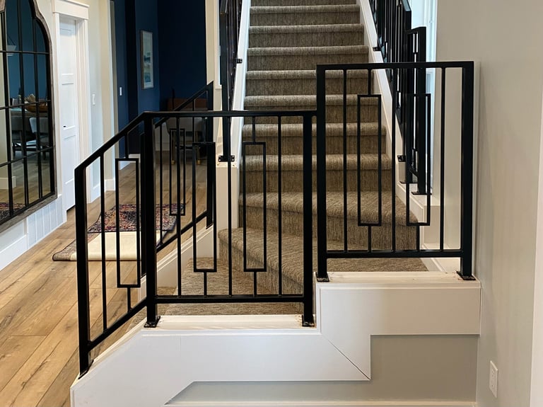 Modern staircase with black metal railings and spindles leading upward in a bright, contemporary home interior
