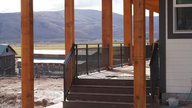 Wooden deck with brown railings and support posts overlooking mountains and valley landscape