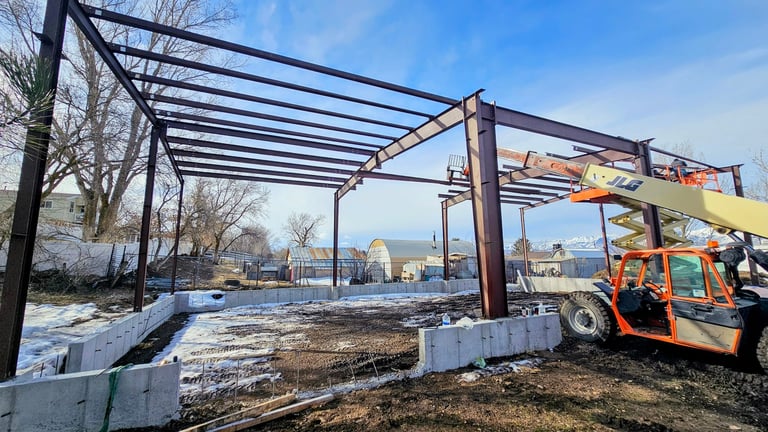 Construction of a metal frame pergola structure with an orange forklift on a snowy winter site