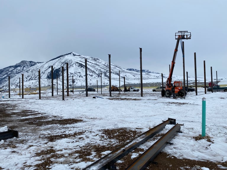 Industrial oil extraction equipment in snowy landscape with derrick, metal framework, and abandoned rails