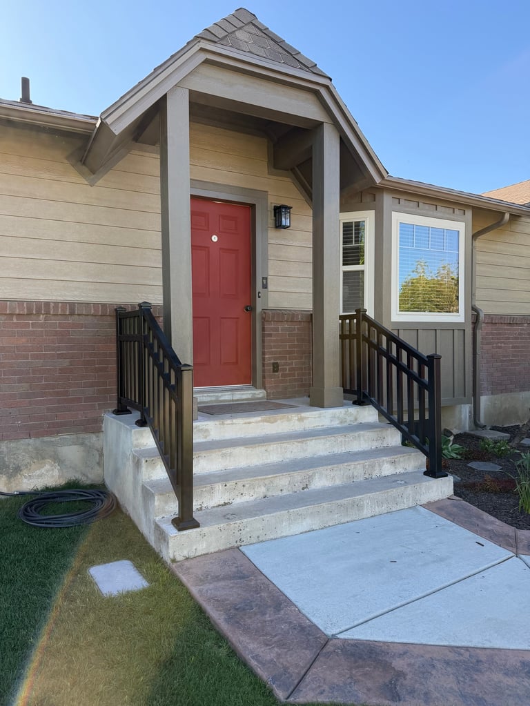 Modern single-story house with red front door, white trim, brick base, and covered entry porch with black railings