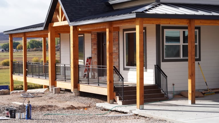 Modern house with wooden beam porch, metal railings, and open covered patio area in rural setting