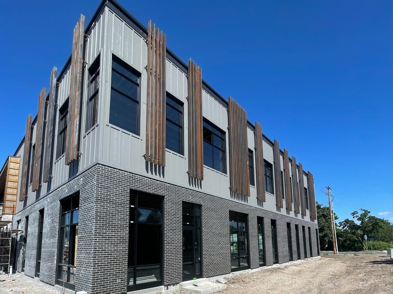Modern building with brick and metal facade under construction against blue sky